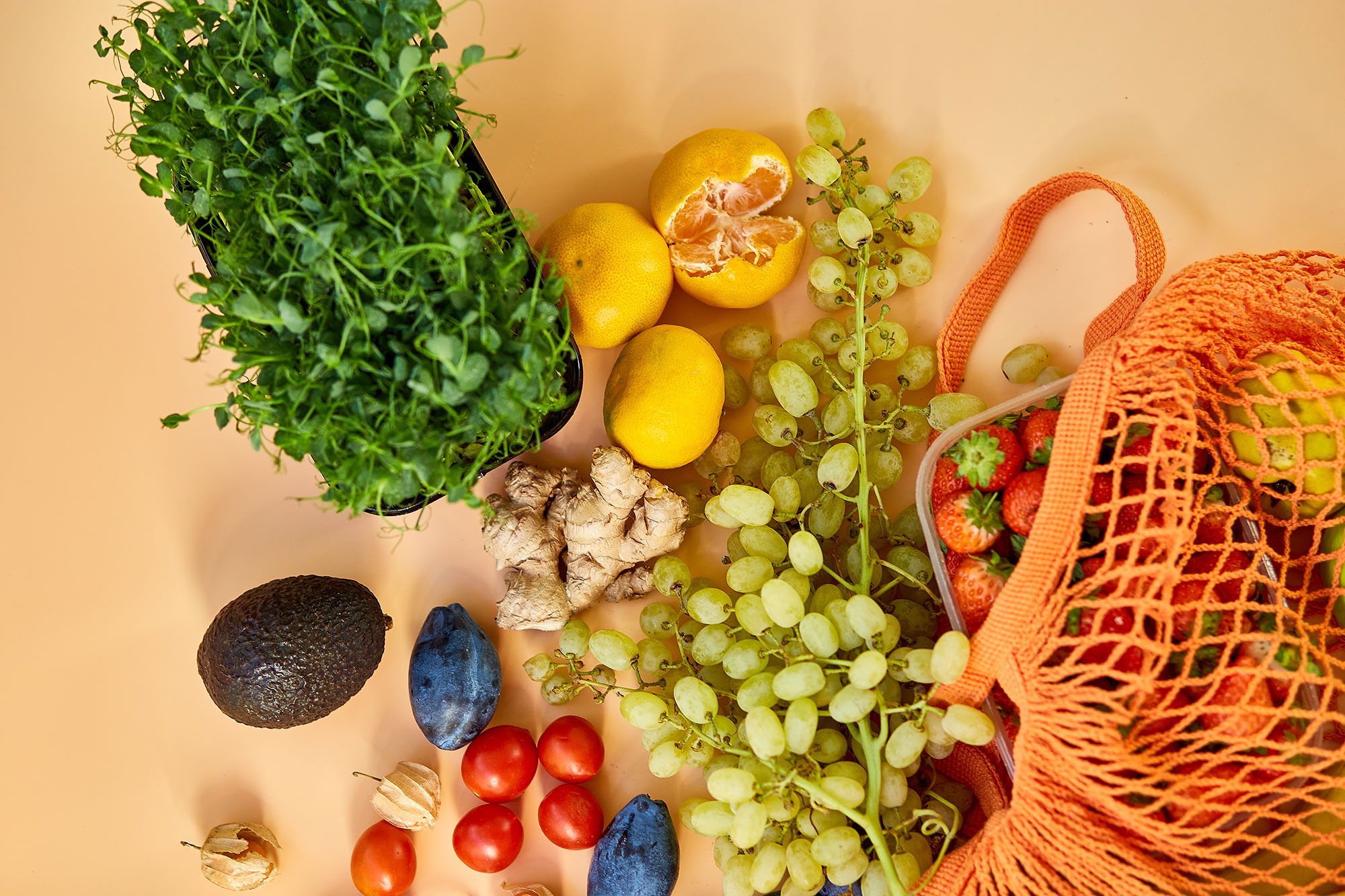 Flat lay Mesh grocery shopping eco friendly bag with fruits on orange canvas background, Zero waste cconcept, Local farmers market, shopping mall, top view, copy space, Plastic free items.